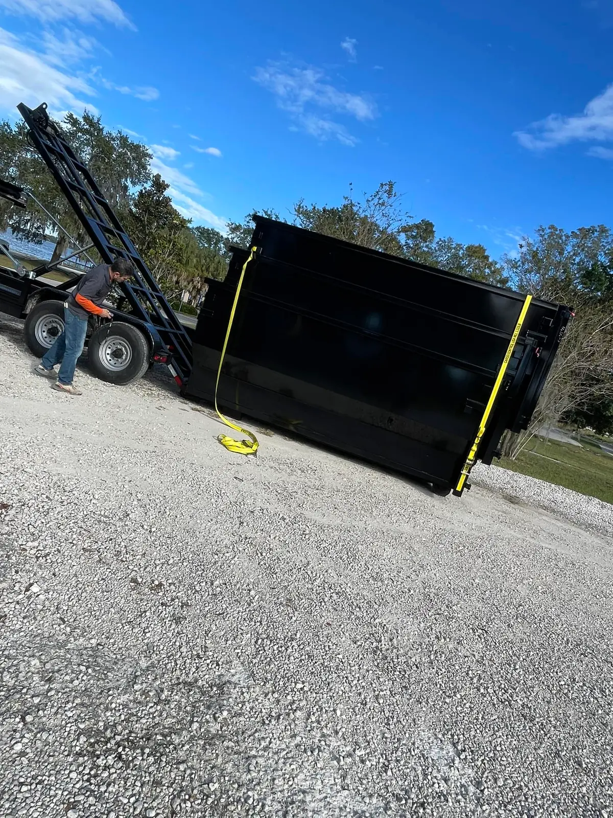 Roll-off dumpster being delivered by trailer