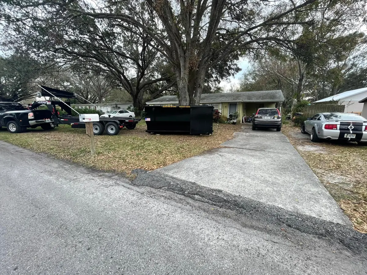 Roll-off dumpster under oak trees ready for yard waste and storm cleanup